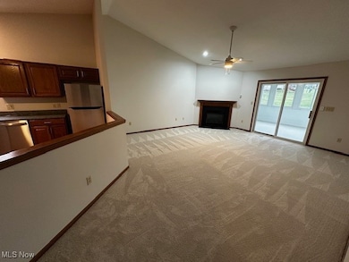 Unfurnished living room featuring a fireplace, light carpet, vaulted ceiling, and a ceiling fan