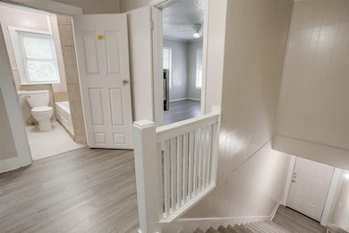 Stairs featuring wood finished floors, plenty of natural light, a ceiling fan, a textured ceiling, and ornamental molding