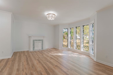 Unfurnished living room with light wood-type flooring and ornamental molding