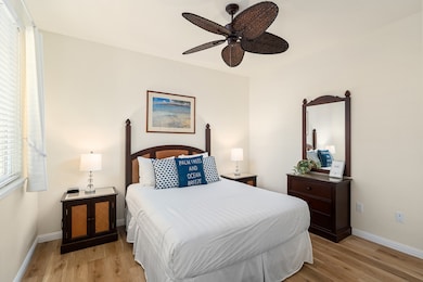Inviting secondary bedroom with a queen bed, matching nightstands, dresser, mirror, and private views overlooking the gated entry lanai.
