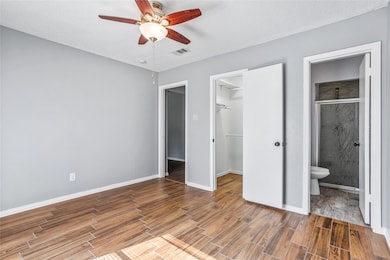 Unfurnished living room featuring a brick fireplace, a textured ceiling, wood finished floors, rail lighting, and ceiling fan