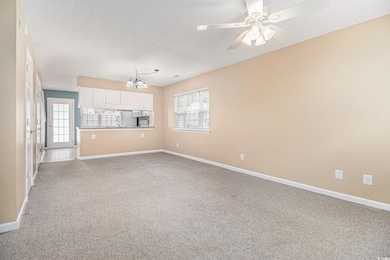 Unfurnished living room featuring light carpet, healthy amount of natural light, and a ceiling fan