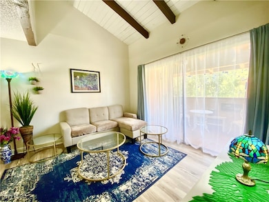 Living room featuring beamed ceiling, wood finished floors, and high vaulted ceiling