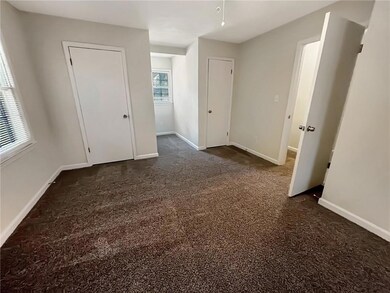 Unfurnished bedroom with dark colored carpet and baseboards