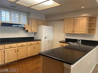 Kitchen featuring open shelves, a sink, dark countertops, visible vents, and white fridge with ice dispenser