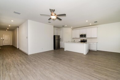 Kitchen with appliances with stainless steel finishes, light hardwood / wood-style floors, white cabinetry, an island with sink, and tasteful backsplash