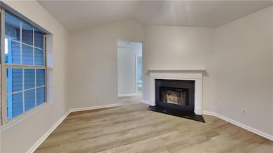 Unfurnished living room featuring baseboards, a fi
