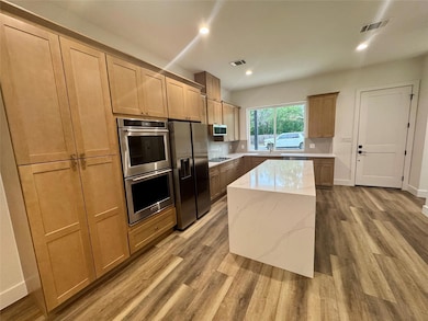Kitchen with wood finished floors, appliances wit