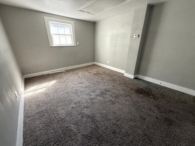 Carpeted spare room with attic access and baseboards
