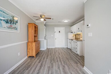 Kitchen with backsplash, light wood finished floors, crown molding, ceiling fan, and white cabinets