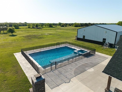 View of pool with fence, a lawn, a rural view, and a pool with connected hot tub