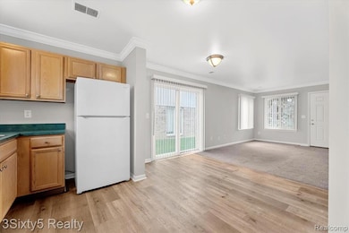 Kitchen featuring freestanding refrigerator, crown molding, dark countertops, healthy amount of natural light, and open floor plan
