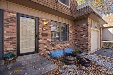 Property entrance featuring board and batten siding, brick siding, an attached garage, and roof with shingles