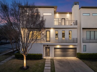 Modern home featuring a balcony, stucco siding, a garage, and driveway