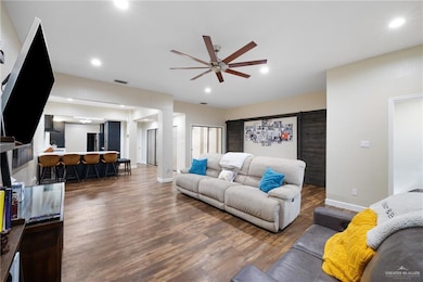 Living room with a ceiling fan, wood finished floors, recessed lighting, and a barn door