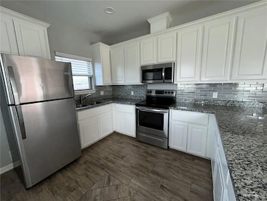 Kitchen featuring stainless steel appliances, white cabinets, dark stone counters, tasteful backsplash, and recessed lighting