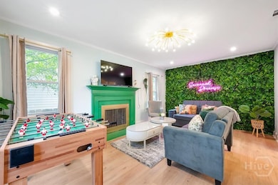 Inviting living room with artificial plant feature wall, fuseball table, woodburning fireplace, and TV.