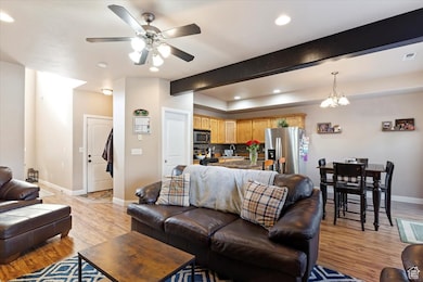 Living area with beamed ceiling, light wood finished floors, recessed lighting, a ceiling fan, and a chandelier