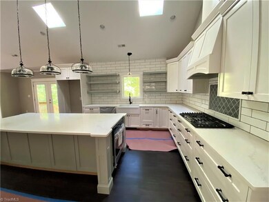 Huge kitchen with custom cabinetry including open shelves, quartz countertops, Island has built in oven, microwave drawer and charging station.