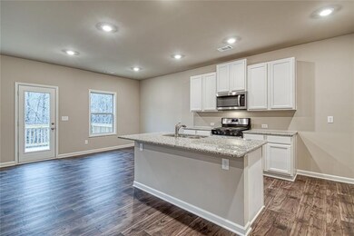 Kitchen with appliances with stainless steel finishes, white cabinets, recessed lighting, light stone countertops, and dark wood finished floors