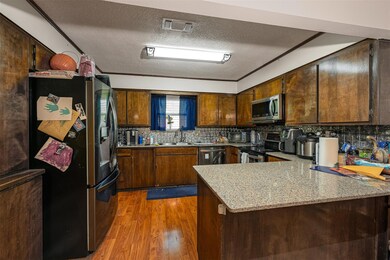 Kitchen with a textured ceiling, a peninsula, ligh