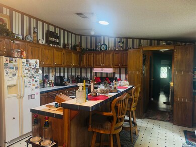 Kitchen with white refrigerator with ice dispenser, tile counters, light floors, a center island, and a kitchen bar