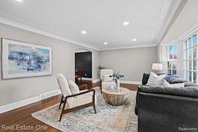 Living area featuring arched walkways, dark wood-type flooring, ornamental molding, and recessed lighting