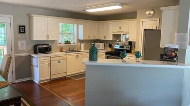Kitchen featuring stainless steel appliances, under cabinet range hood, white cabinets, and light countertops