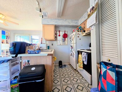 Kitchen with ceiling fan, stove, white fridge, tra