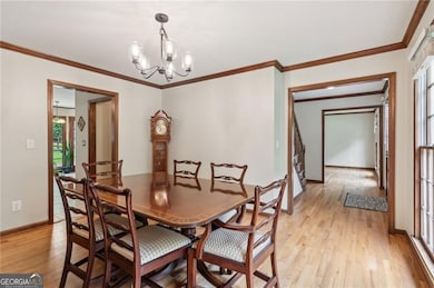 Dining space with light wood finished floors, a chandelier, baseboards, and crown molding