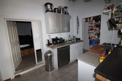 Kitchen with light tile patterned floors, dishwashing machine, and light countertops