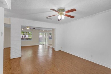 Spare room featuring wood-type flooring, a textured ceiling, ceiling fan, and crown molding