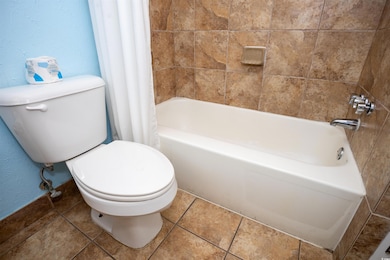 Bathroom with tile patterned floors, toilet, showe