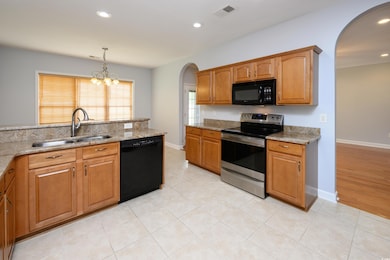 Kitchen featuring black appliances, a sink, arched