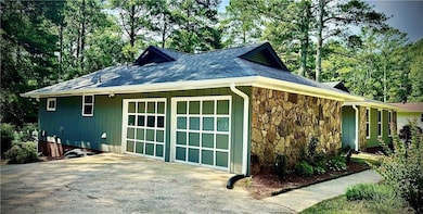 View of side of home featuring stone siding, concrete driveway, and roof with shingles
