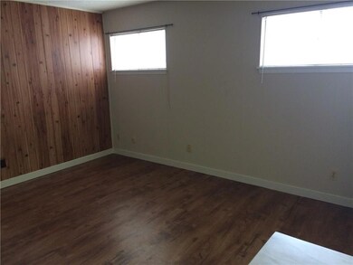 Unfurnished room with wooden walls and dark wood-type flooring