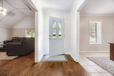 Foyer featuring a ceiling fan, wood finished floors, baseboards, and ornamental molding