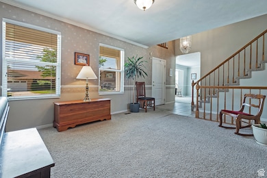 Sitting room featuring carpet, wallpapered walls, stairway, and crown molding