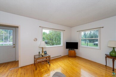 Living area featuring a baseboard radiator, light wood-style flooring, plenty of natural light, and a textured ceiling