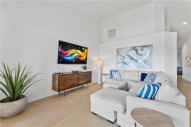 Living room with light wood-style flooring, a high ceiling, and baseboards