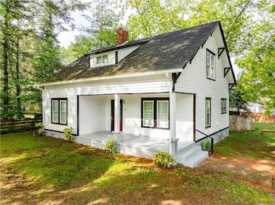 View of front of home with a chimney, covered porch, and roof with shingles