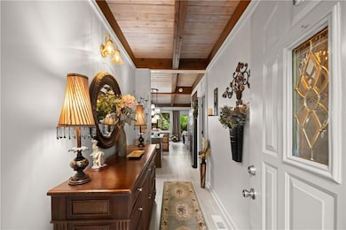 Corridor with wood ceiling with exposed beams, light wood-style floors, and baseboards