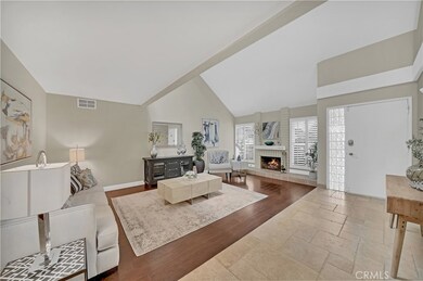 Entry Door with Glass Block Sidelight Opens to Travertine Raised Foyer and Large Formal Living Room with Soaring Ceiling and Fireplace with Raised Travertine Hearth