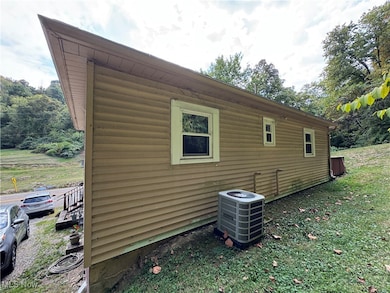 View of side of home with a central AC unit and a lawn