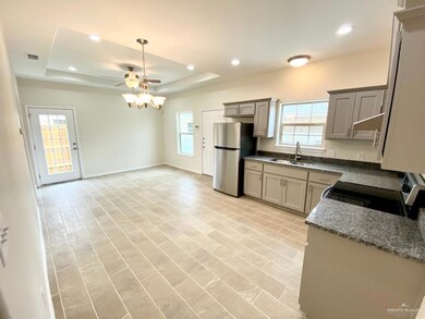Kitchen with freestanding refrigerator, range with electric cooktop, a raised ceiling, ceiling fan, and recessed lighting