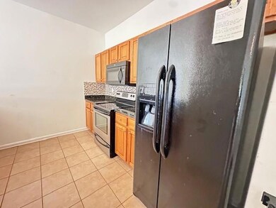 Kitchen featuring black appliances, dark countertops, light tile patterned flooring, and backsplash