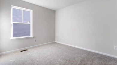 Carpeted secondary bedroom in a DRB Homes Cranberry plan at the Village of College Park community.