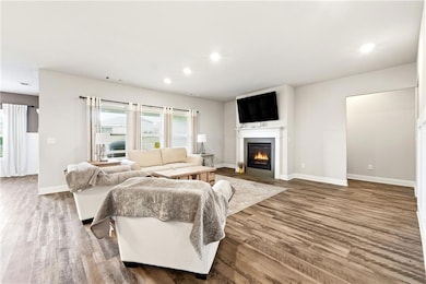 Living room featuring a fireplace with flush hearth, wood finished floors, and recessed lighting