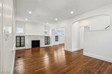 Living room with a healthy amount of sunlight, dark hardwood flooring, crown molding, and a brick fireplace