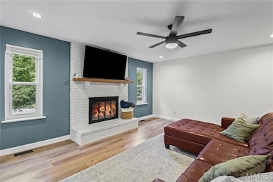 Living room featuring a brick fireplace, wood finished floors, and recessed lighting